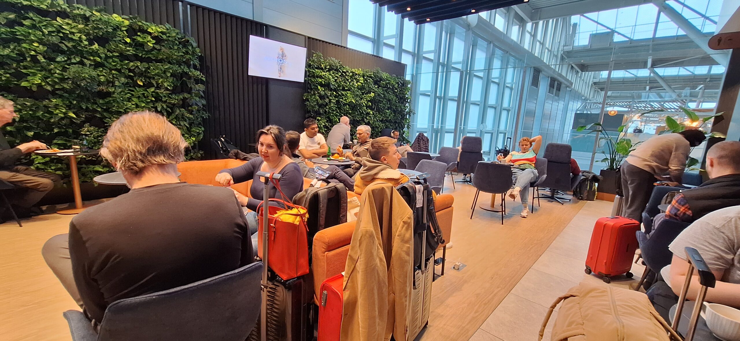 LOT Business Lounge review a group of people sitting in a room with chairs and a large window