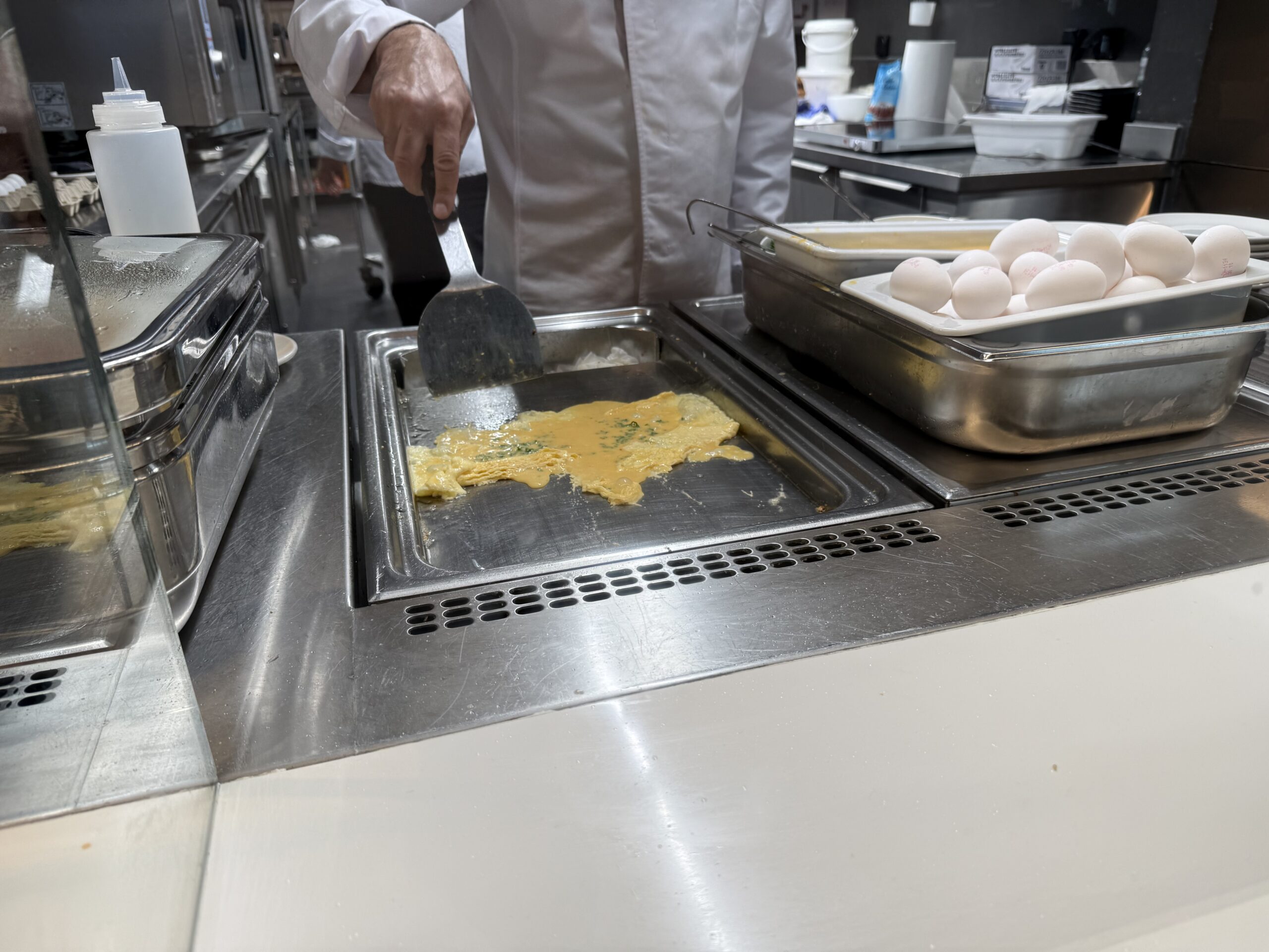 Swiss Senator Lounge Zurich Terminal A Review a person cooking eggs in a kitchen