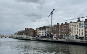 a bridge over water with buildings and cranes