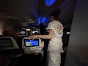a woman in a white dress standing in an airplane with a screen on the back
