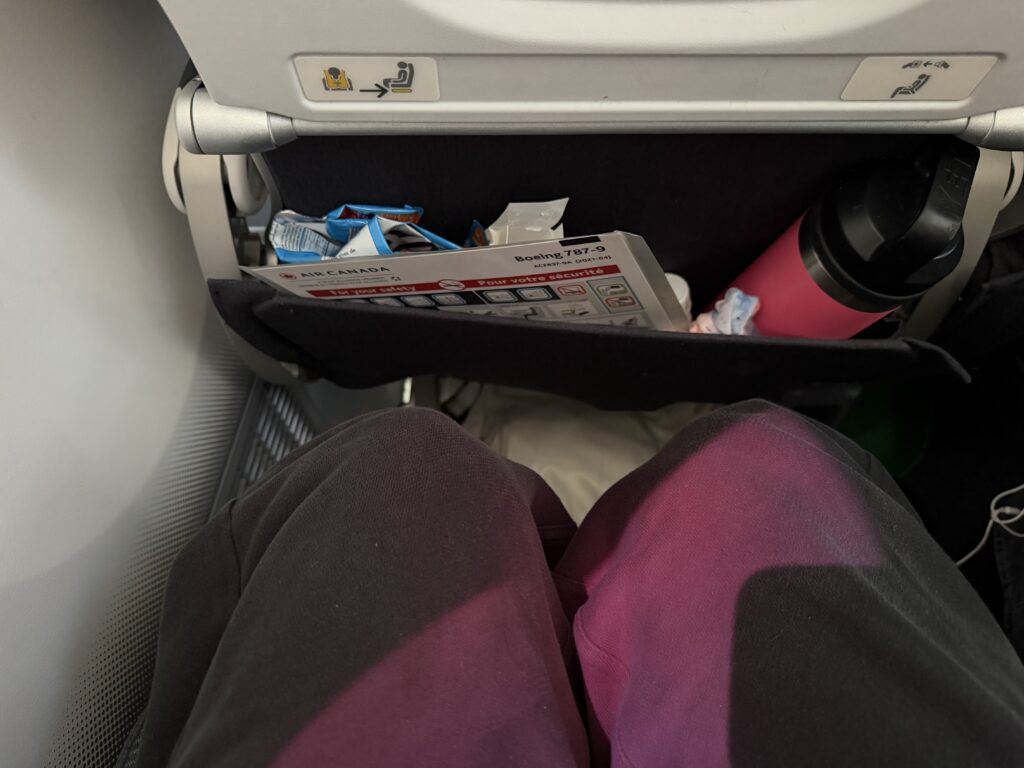 a person's legs in a chair with a shelf in the back