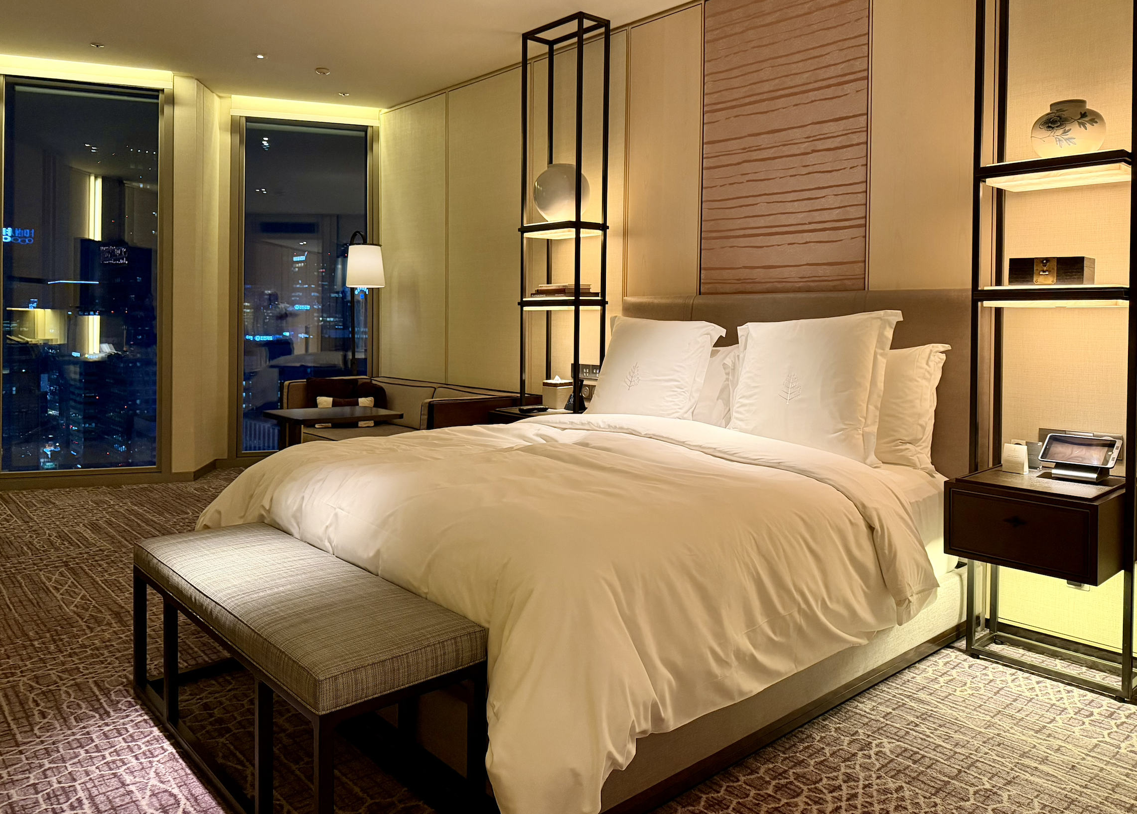 a bed with white sheets and pillows in a room