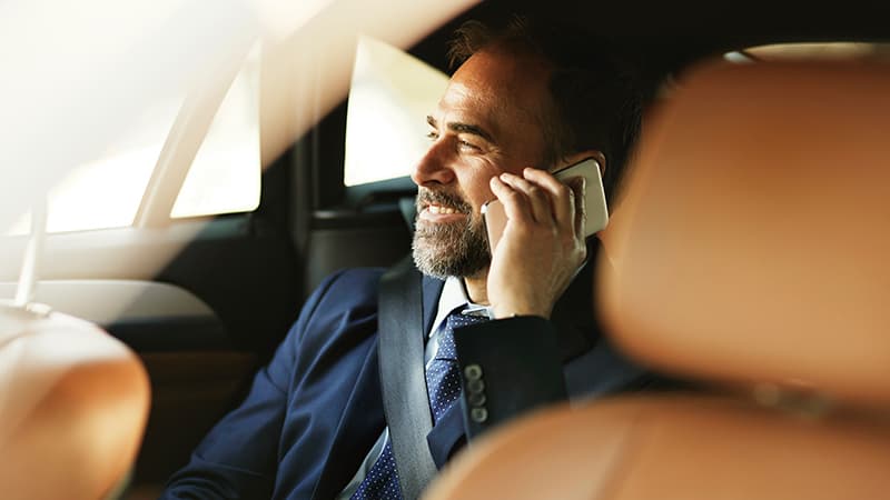 a man in a suit talking on a cell phone in a car