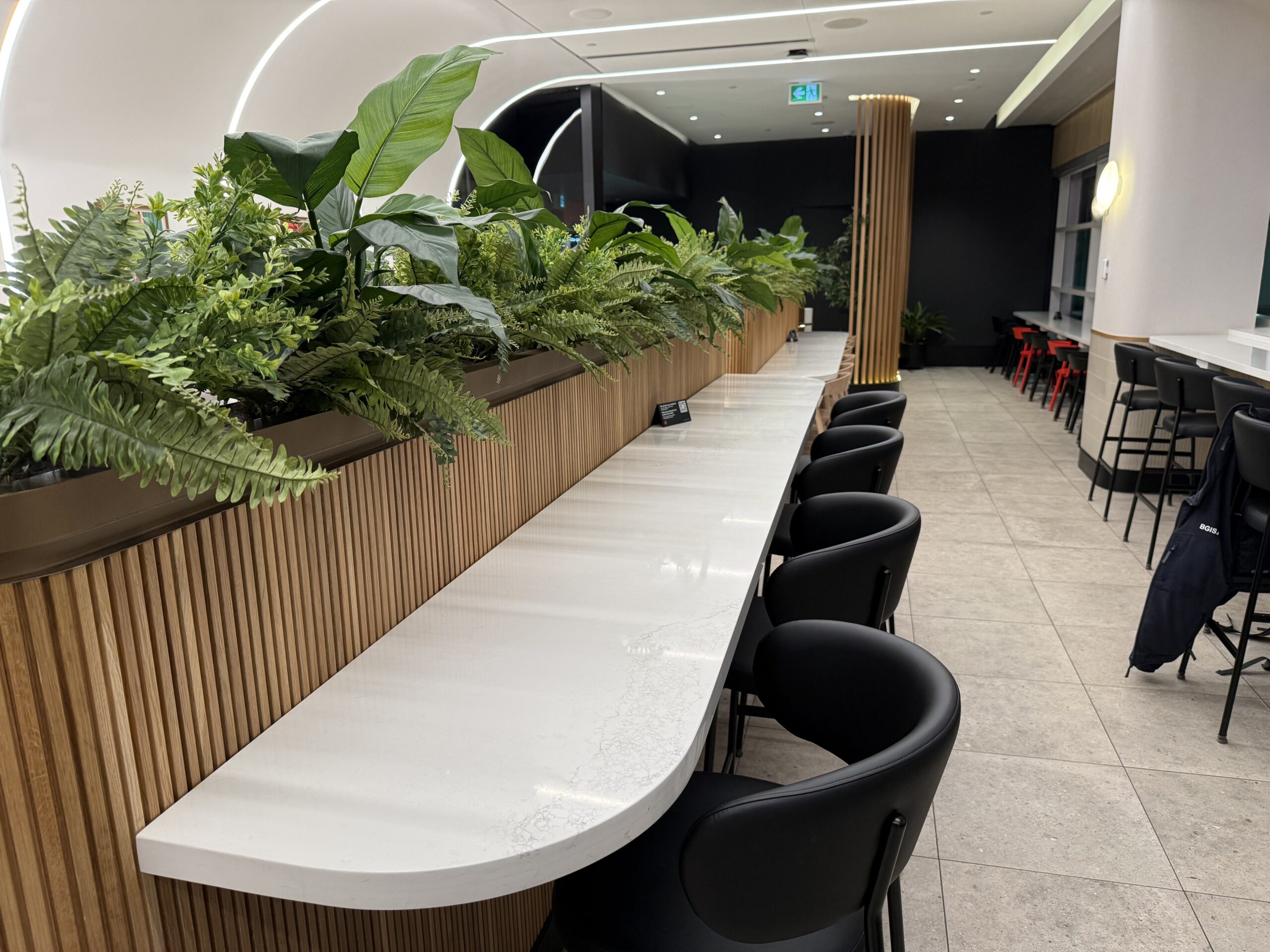 Air Canada Cafe YVR C47 a long white table with black chairs and plants in a room