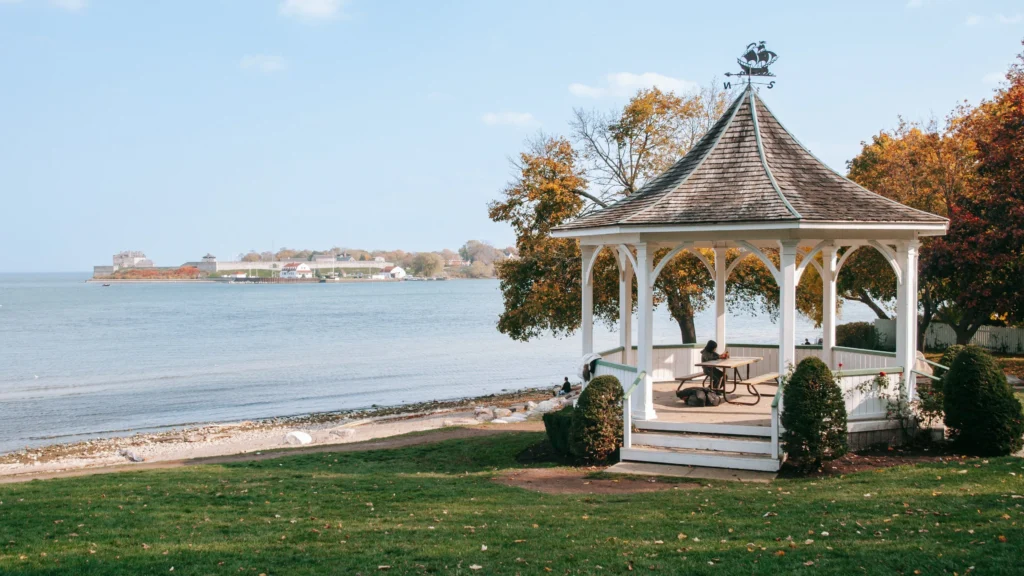 a gazebo with a person sitting at a table by the water