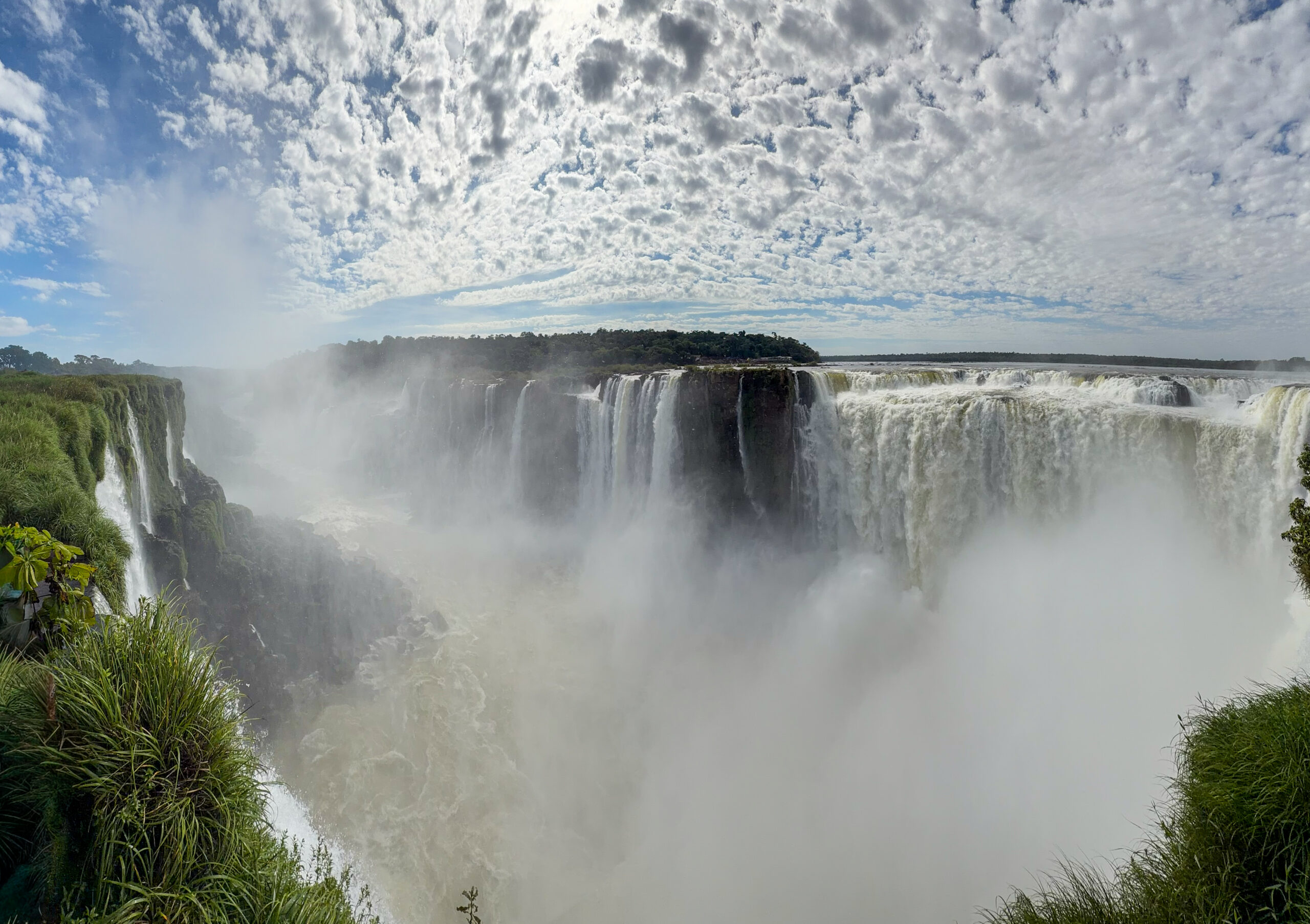 a large waterfall with clouds in the sky