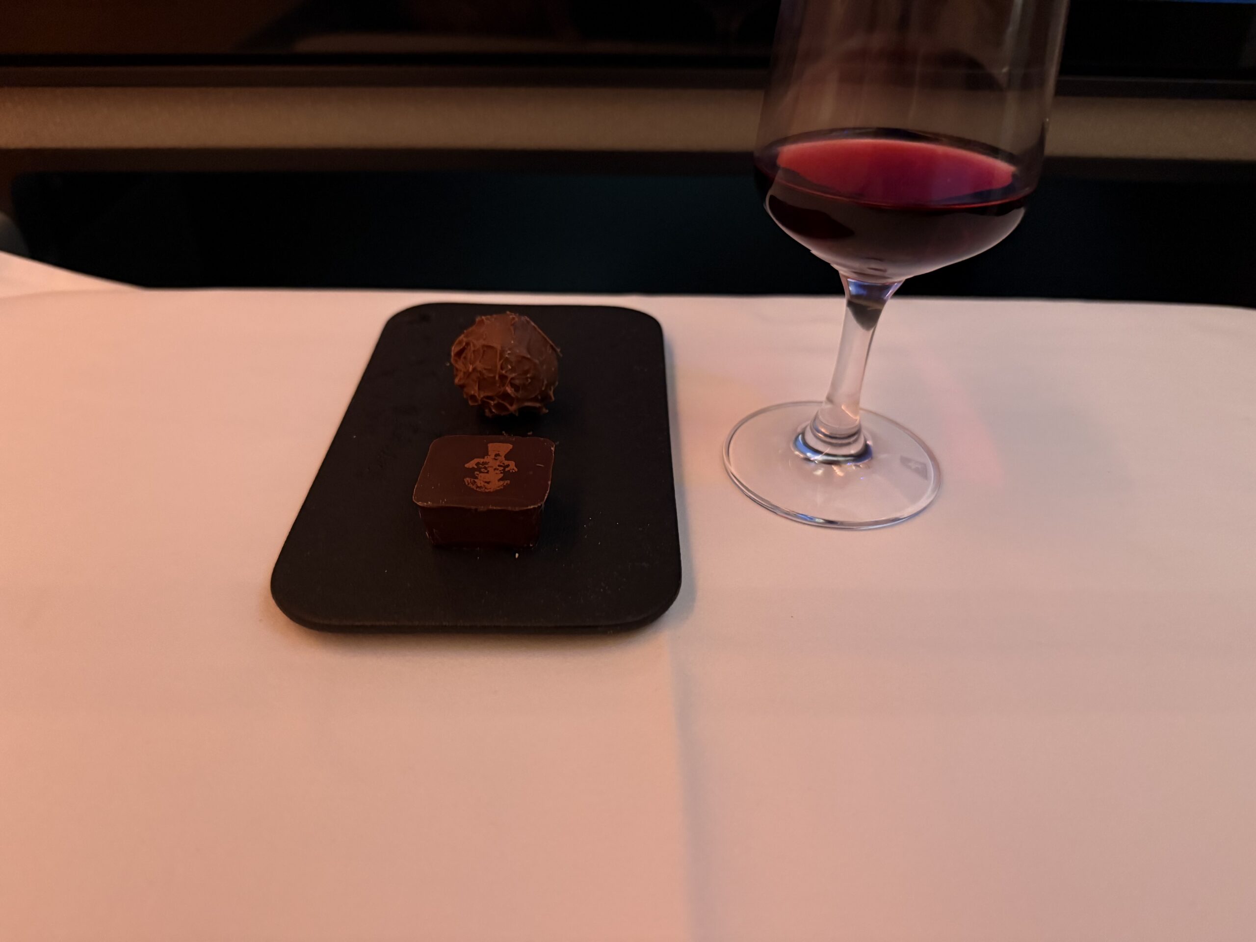 a glass of wine and chocolate on a table