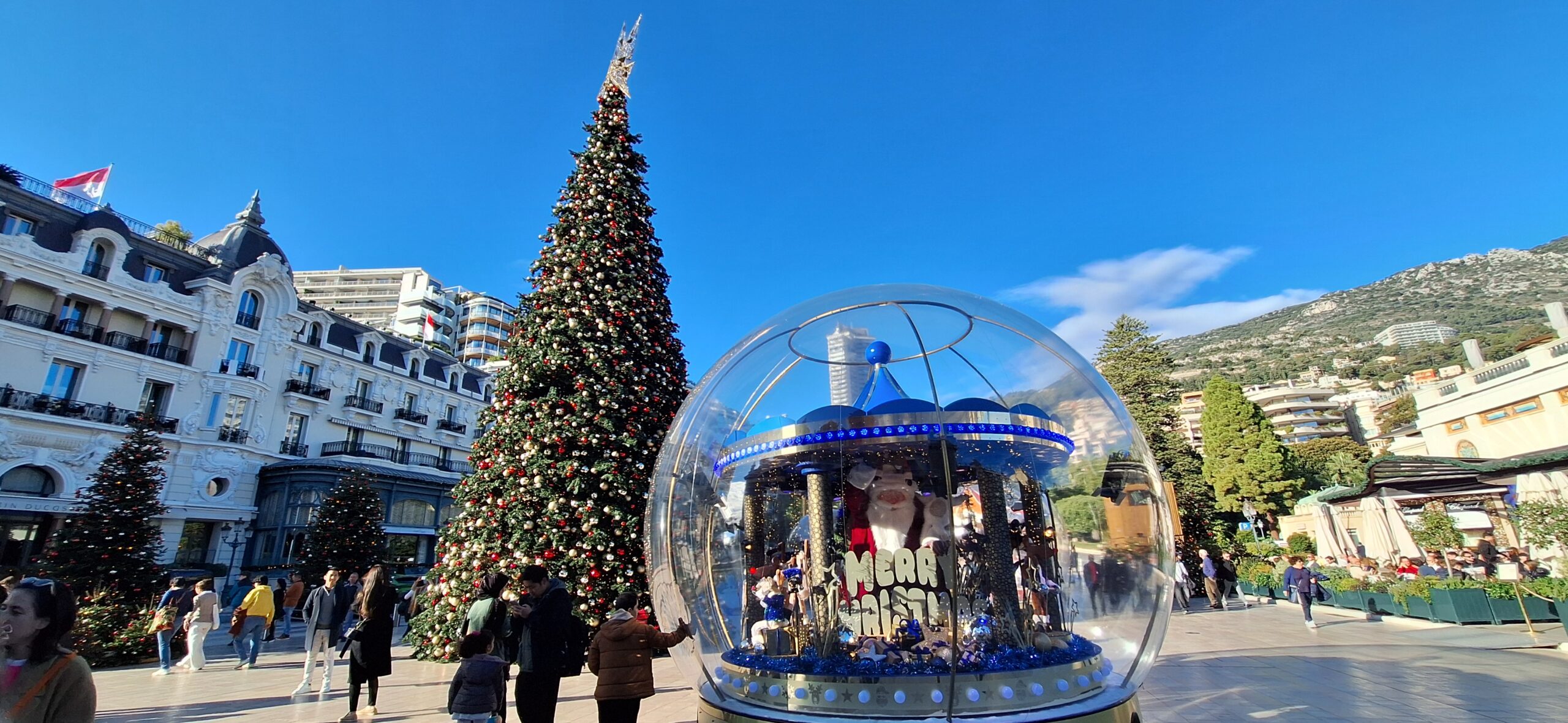 a large glass ball with lights and a christmas tree in the background