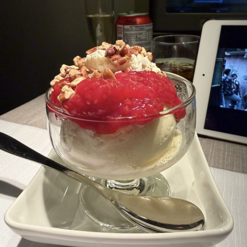 a bowl of ice cream with red sauce and nuts
