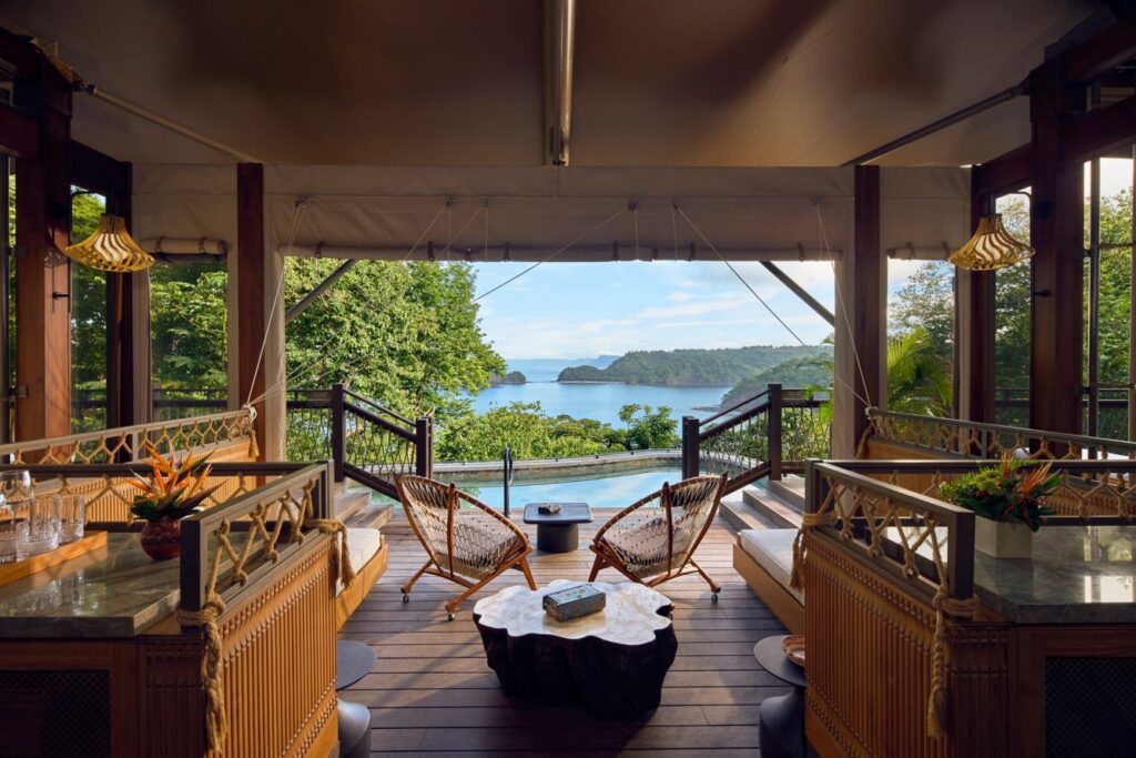 a deck with chairs and a table overlooking a body of water