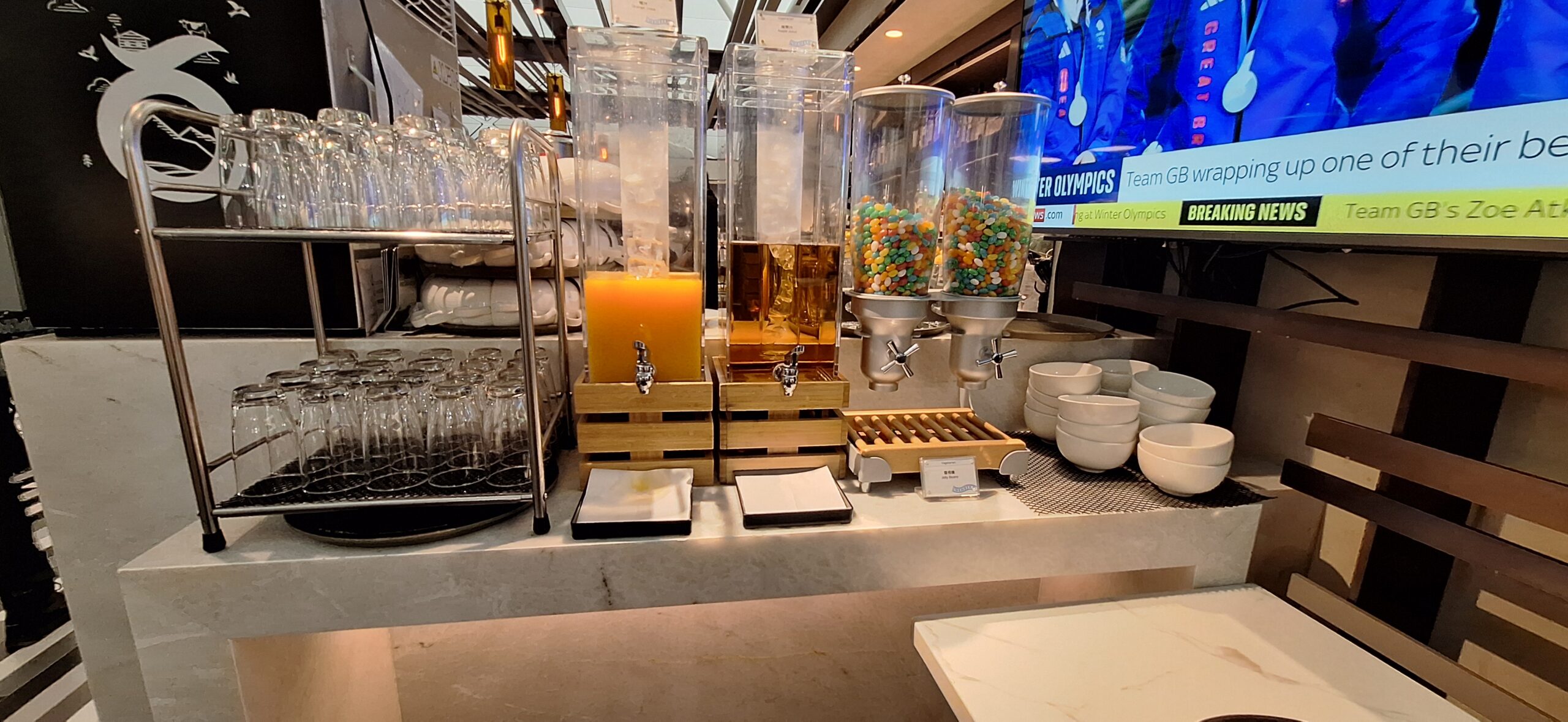 Centurion Lounge Hong Kong a group of containers with candy and orange liquid on a table