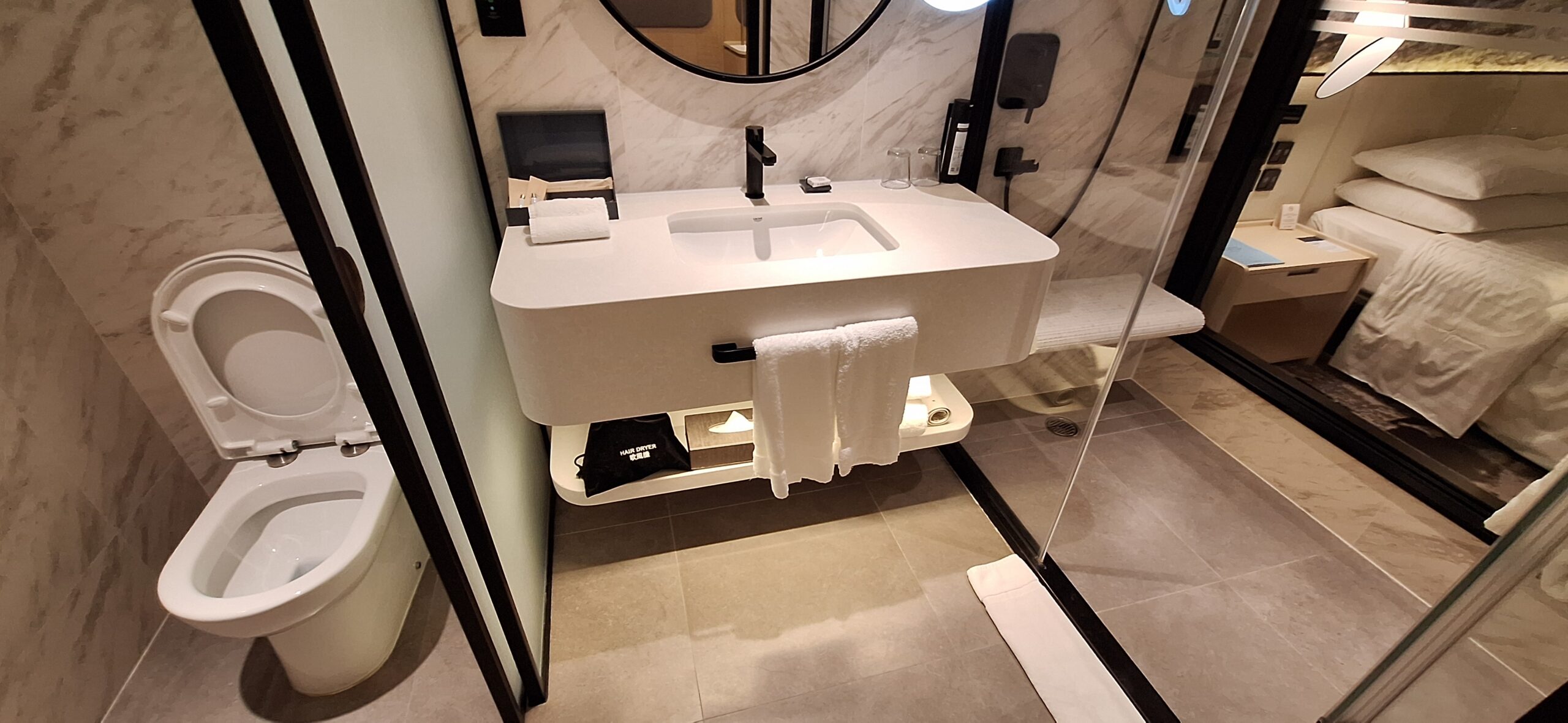 The Park Lane Hong Kong Review a bathroom with a round mirror and a sink