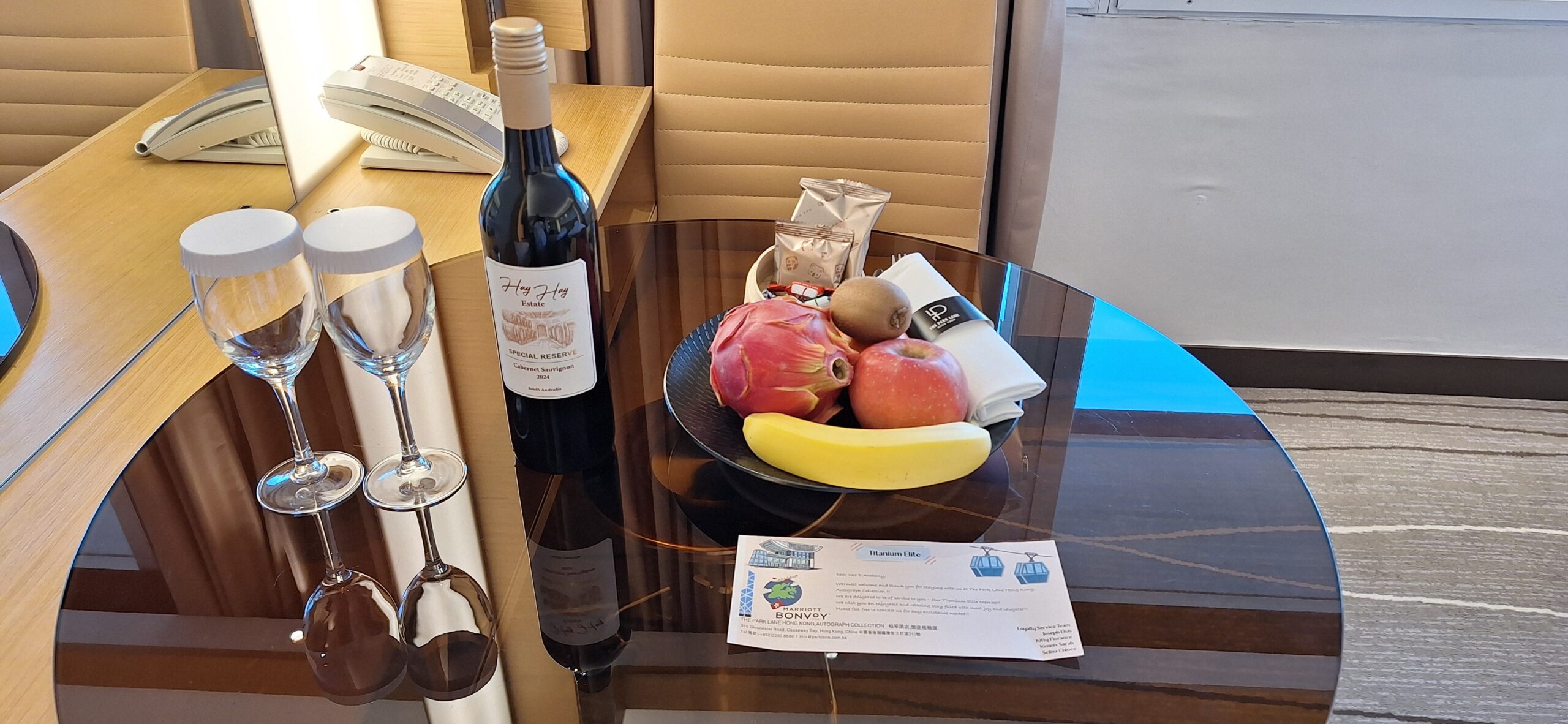 The Park Lane Hong Kong Review a bowl of fruit and a bottle of wine on a glass table