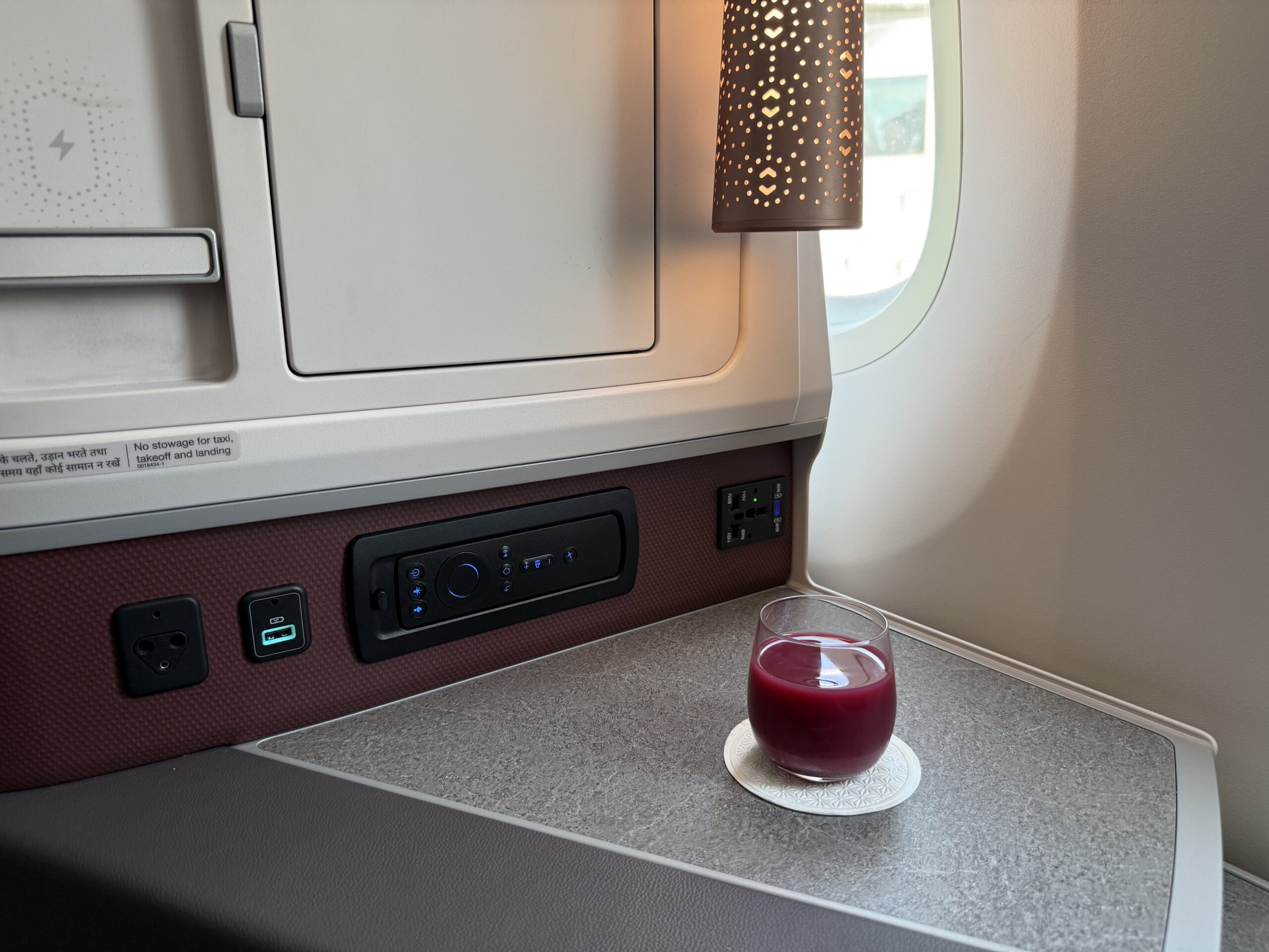 Air India 787-9 Business Class a glass of red liquid on a table in an airplane