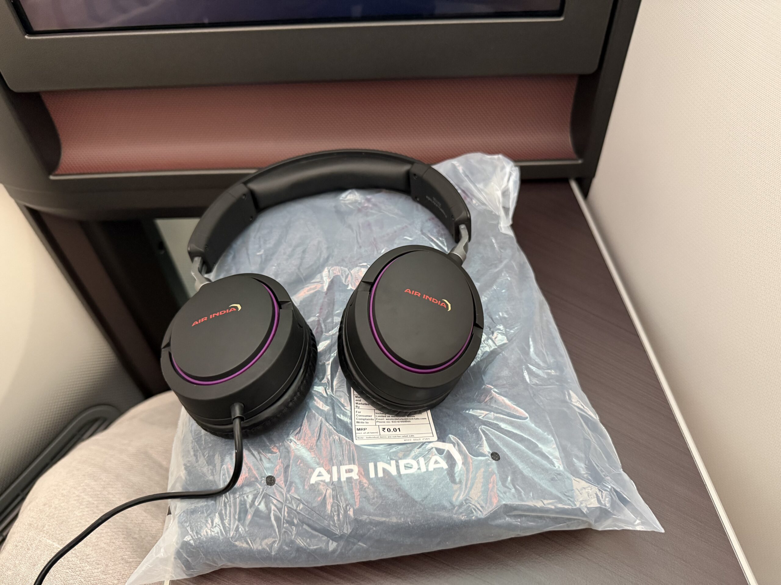 Air India 787-9 Business Class a pair of black headphones on a plastic bag