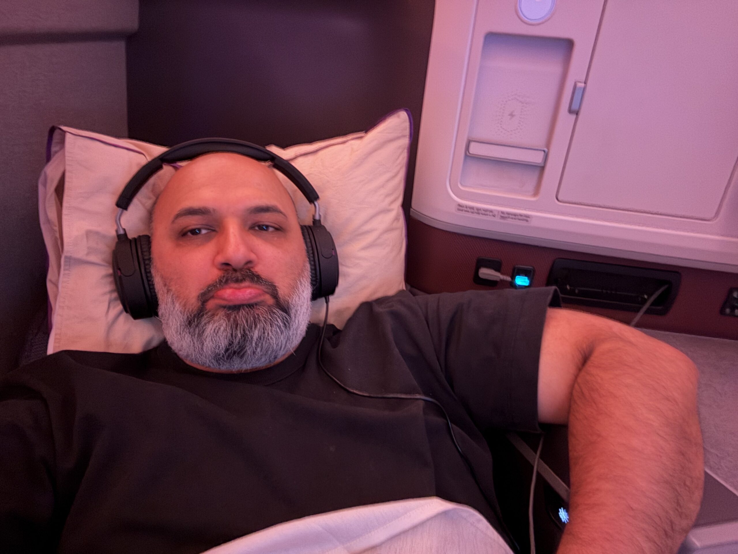 Air India 787-9 Business Class a man lying in a bed with headphones