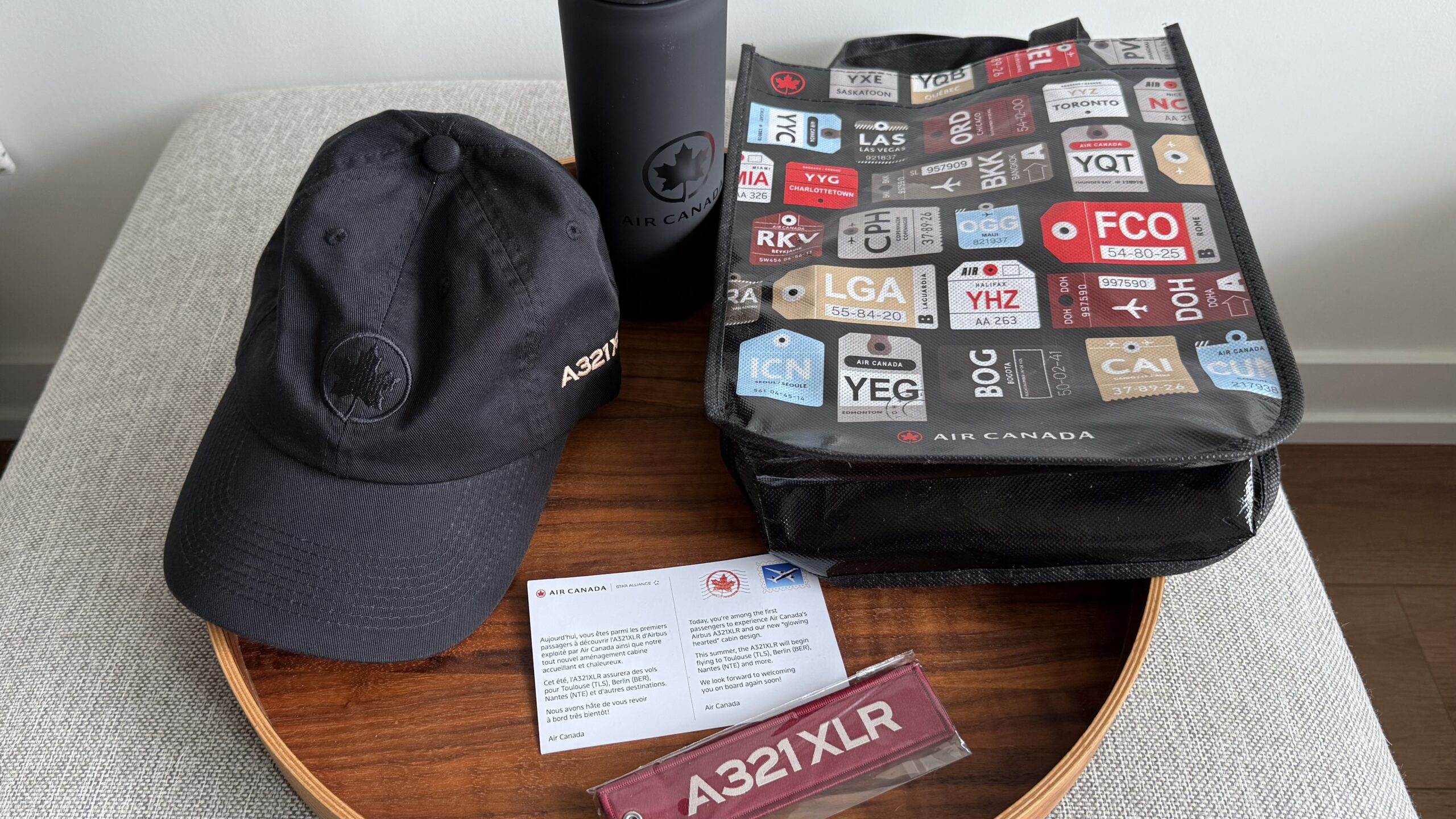 Inaugural Air Canada A321XLR a black bag and a black cap on a wooden tray