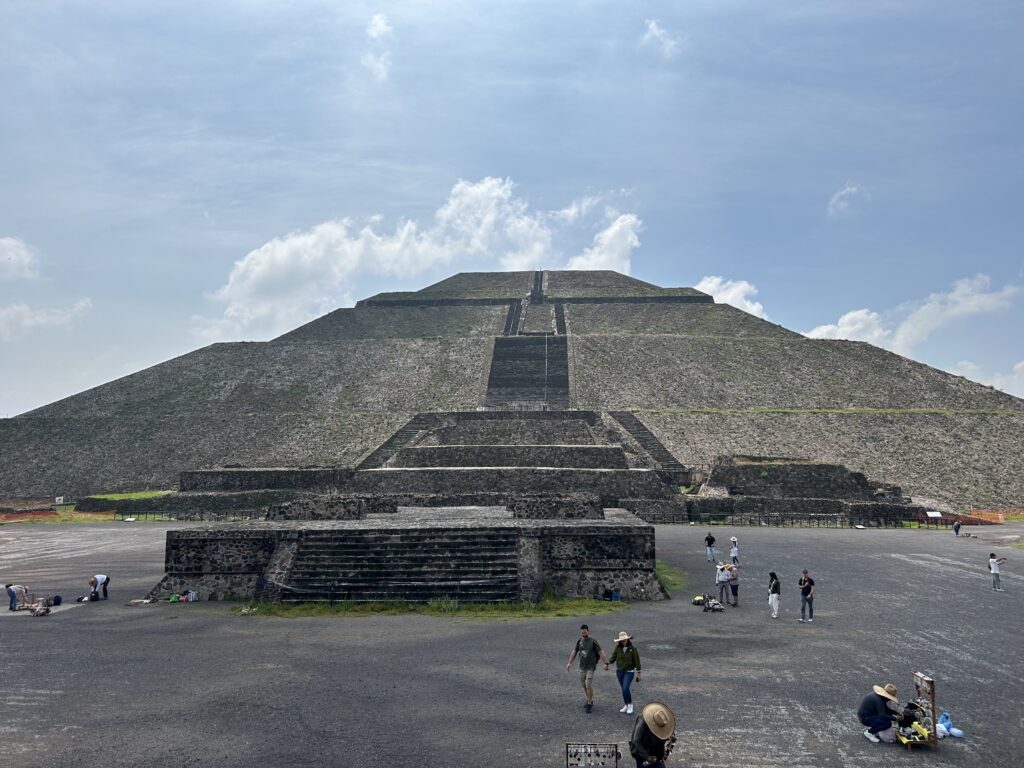 a group of people walking around a pyramid with Pyramid of the Sun in the background