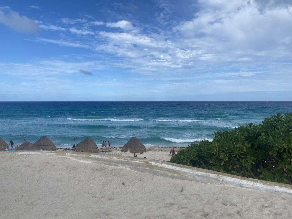 a beach with a group of huts and a body of water