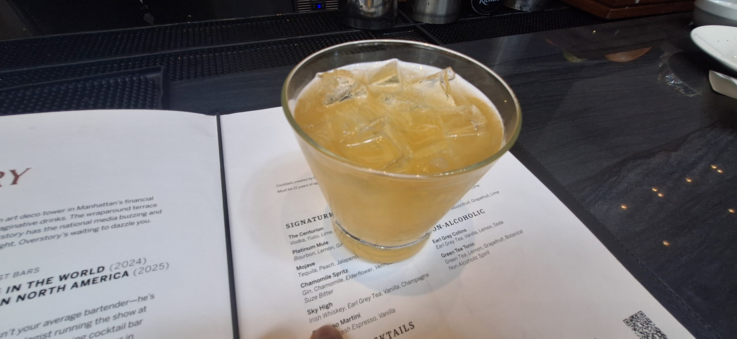 a glass of liquid with ice on a paper