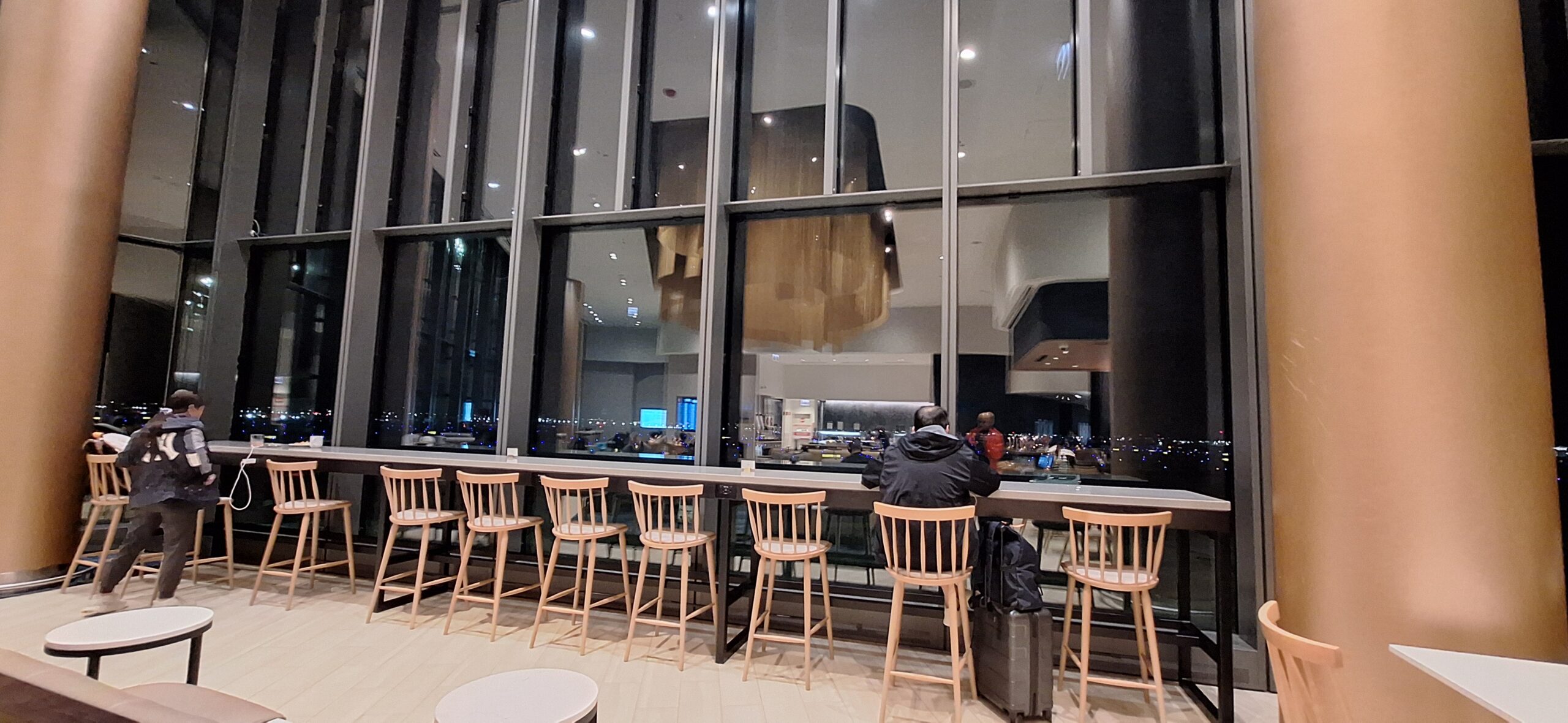 LOT Business Lounge ORD a group of people sitting at a counter in a room with large windows
